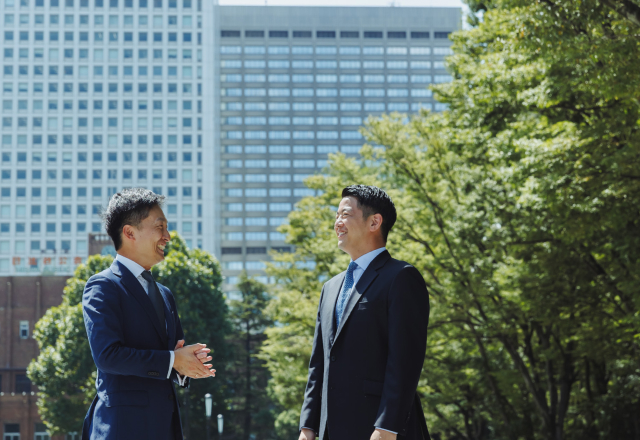 二人のスーツを着た男性がこちらを向いて立っている