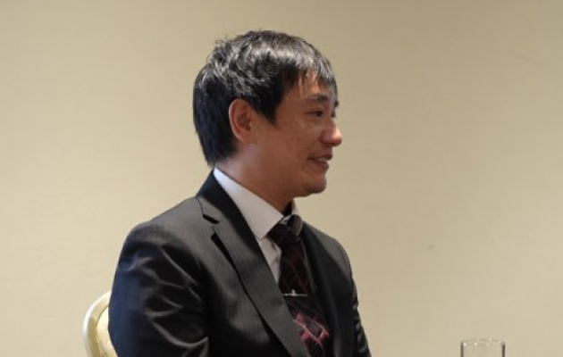 インタビューに応じるスーツ姿の男性